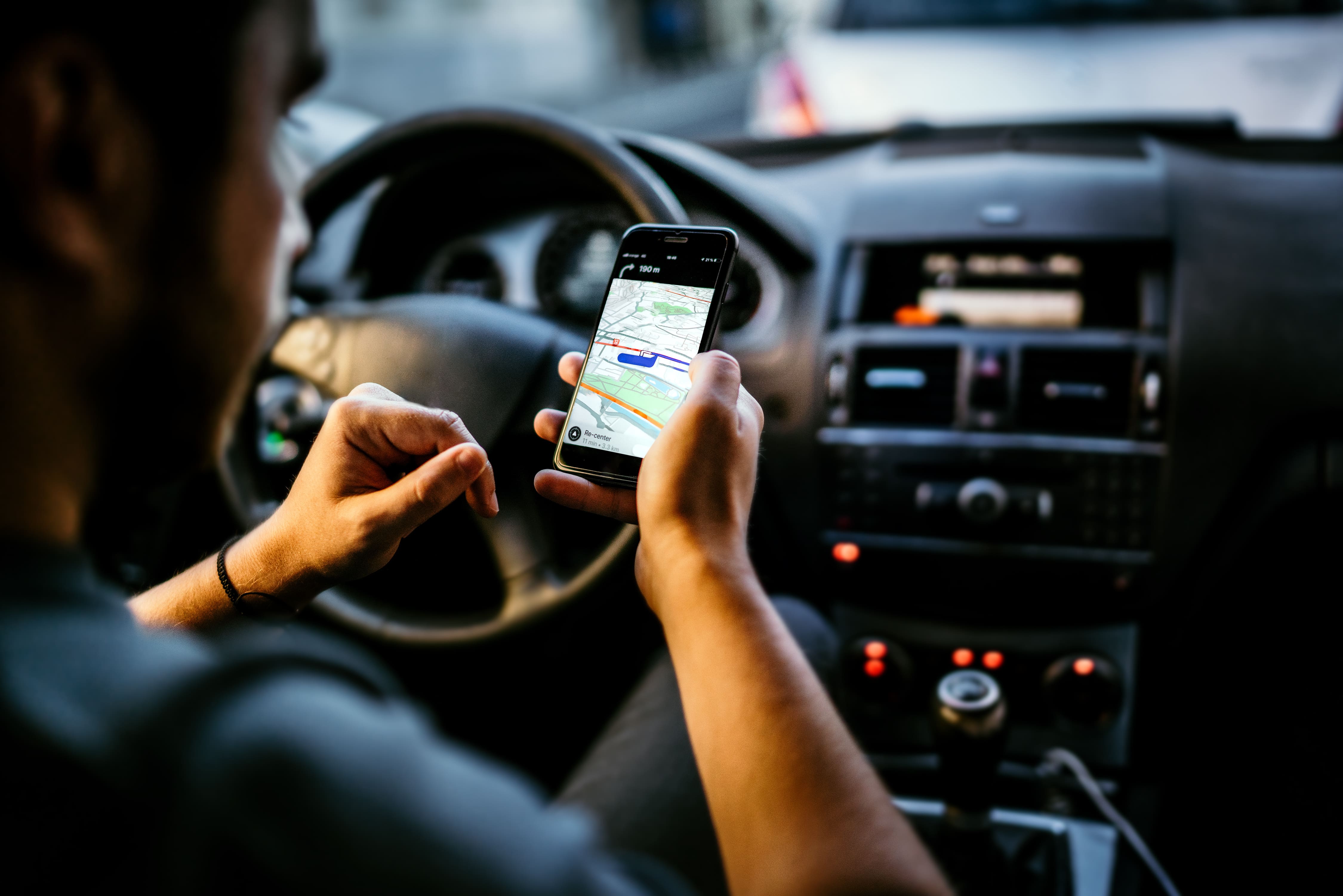 homme dans sa voiture qui regarde le GPS sur son téléphone