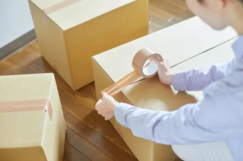 femme qui ferme un carton avec du scotch